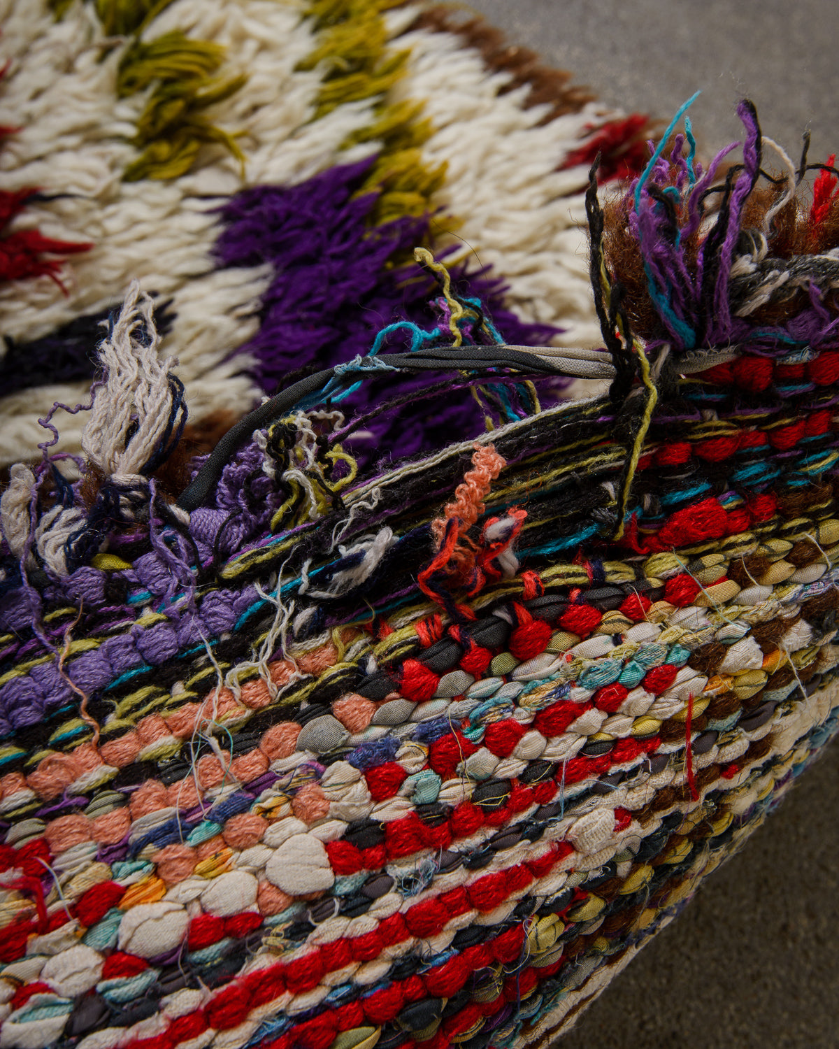 Edge of vintage rug showing a hole in the weaving.